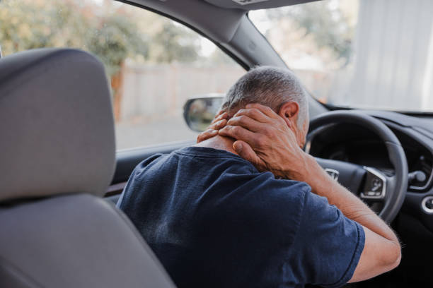 Middle-aged man holding his neck in pain after a car accident